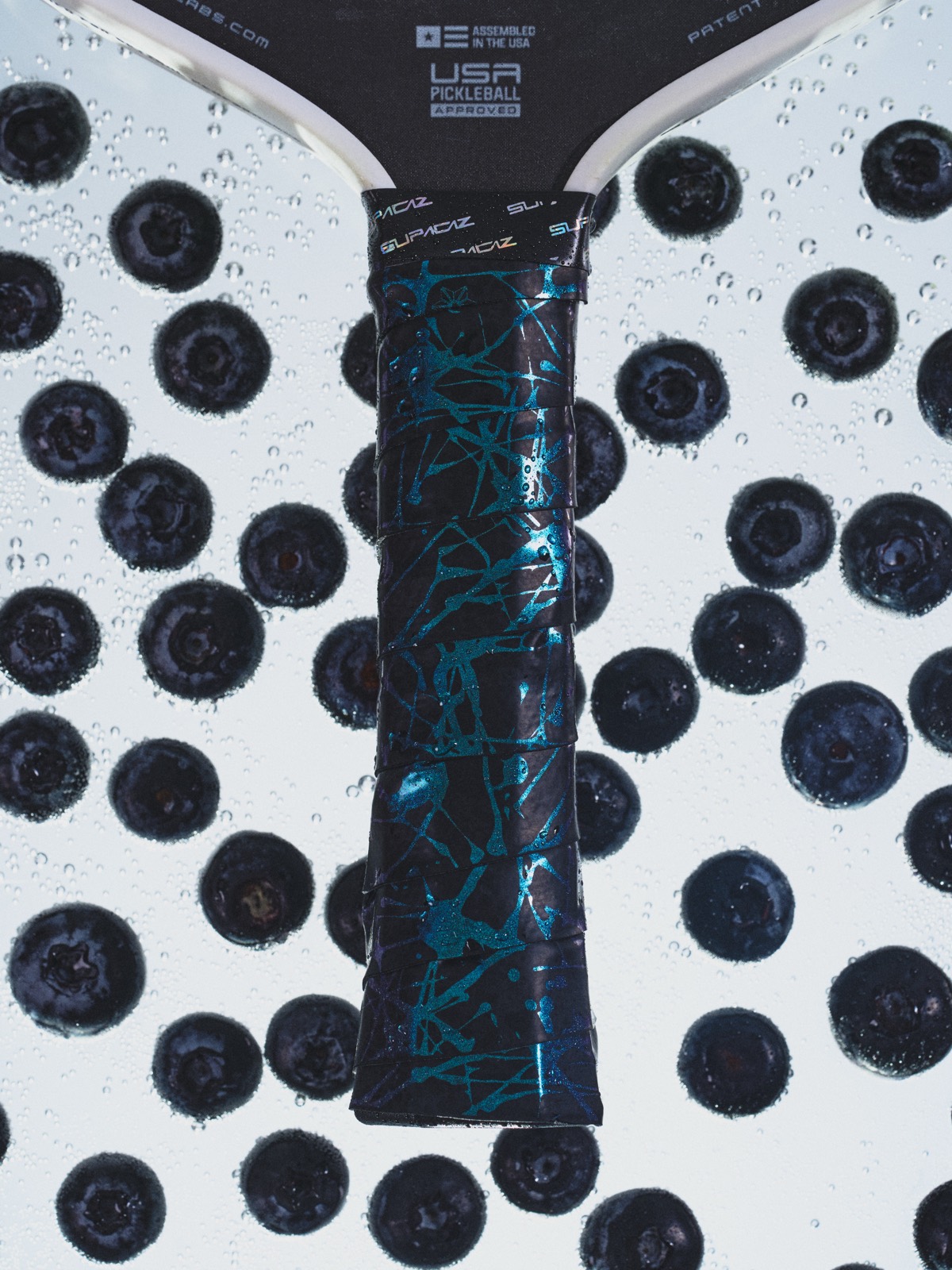 A blue Supacaz grip on a paddle among blueberries